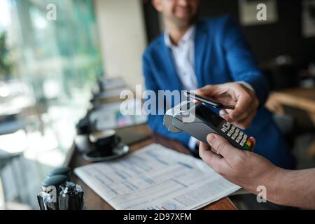 Waiter and customer using nfc technology in a cafe Stock Photo