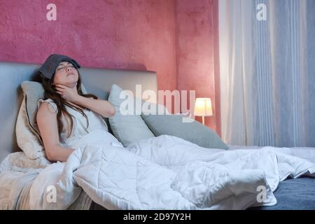 Adolescent girl suffers from a severe sore throat and finds herself lying in bed in her room with fever. Stock Photo