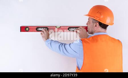 Housebuilder Using Building Level Standing Back To Camera, White Background Stock Photo