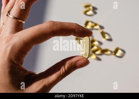Feminine hand holding yellow capsule close up Stock Photo