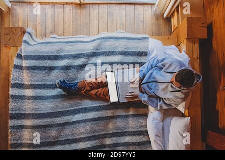Man working on laptop sitting on cozy bed Stock Photo