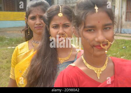 Close up of three teenage Indian girls wearing sari golden nose ring maang tikka necklace earrings with make up, selective focusing Stock Photo