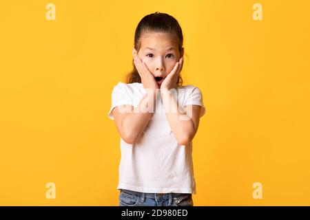 Asian girl with open mouth touching cheeks in excitement Stock Photo