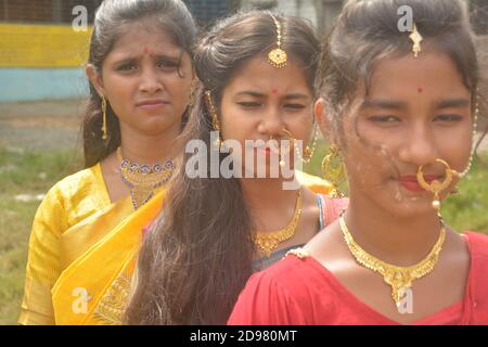 Close up of three teenage Indian girls wearing sari golden nose ring maang tikka necklace earrings with make up, selective focusing Stock Photo