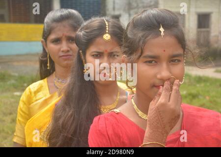 Close up of three teenage Indian girls wearing sari golden nose ring maang tikka necklace earrings with make up, selective focusing Stock Photo