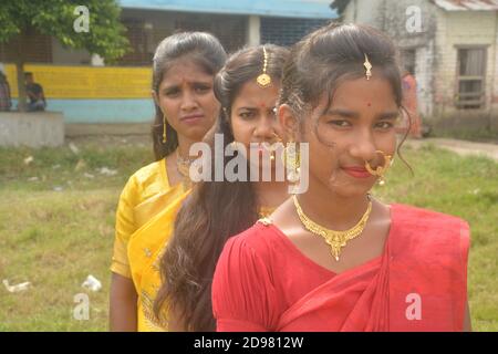 Close up of three teenage Indian girls wearing sari golden nose ring maang tikka necklace earrings with make up, selective focusing Stock Photo