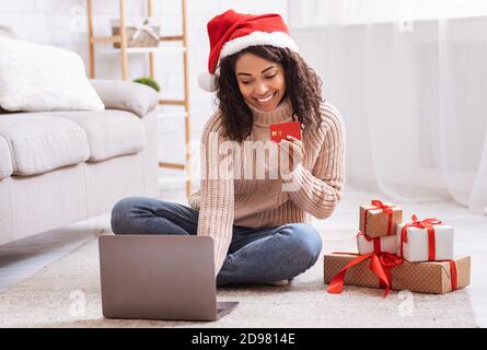 Online Shopping. Black lady using laptop showing credit card Stock Photo