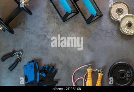 Background with items for training at home. Push up bars, dumbbells, weight plates of different sizes, jump rope, training gloves and hand grip. Stock Photo