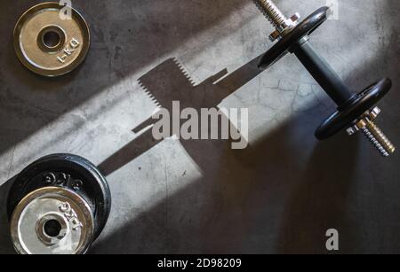 Dumbbells and various weight plates on a concrete surface. Background with empty space. Stock Photo