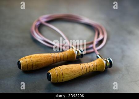 Jump rope with wooden grips. Sports rope for training on concrete surface Stock Photo