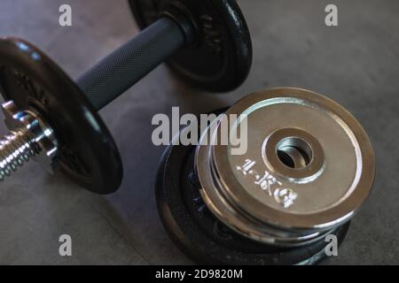 Dumbbell with stacked iron weight plates of different weights and sizes on a concrete surface Stock Photo