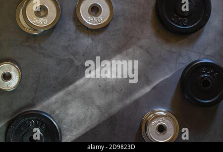 Weight plates of different weights, sizes and colors on a concrete surface with empty space Stock Photo