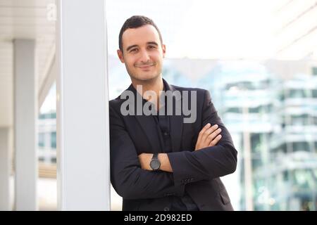 Portrait of businessman leaning against post outside in the city Stock Photo