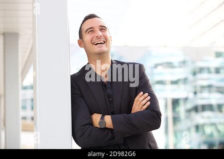 Portrait of happy businessman leaning against post outside in the city Stock Photo