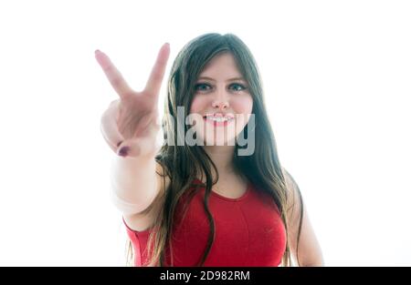 17-year-old teenage girl doing victory symbol with her hands. Photo on white background Stock Photo