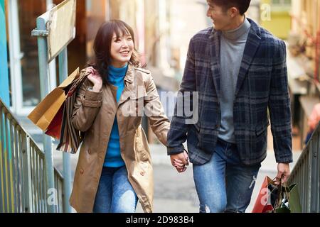 happy young asian couple walking talking holding hands while shopping in the city Stock Photo