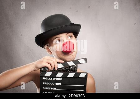 happy little girl holding a movie clapper board on a grey background Stock Photo