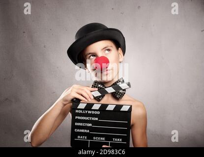 happy little girl holding a movie clapper board on a grey background Stock Photo