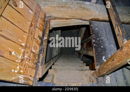 view down a steep old wooden staircase in the roof timbering of the Saint Mary church of Barth, Germany Stock Photo