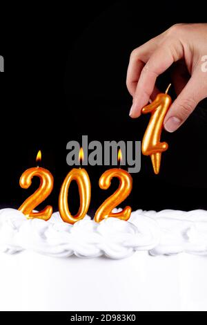 Four golden candles write numbers flame happy new year2021 hand black background Stock Photo