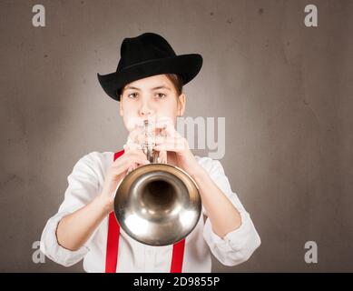 little girl playing trumpet on a gray background Stock Photo