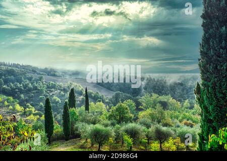 Picturesque green countryside in Tuscany Italy with sun shining through clouds. Stock Photo