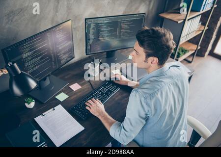 Top above high angle view portrait of his he nice attractive focused skilled geek guy typing bug track report cyberspace security at modern industrial Stock Photo