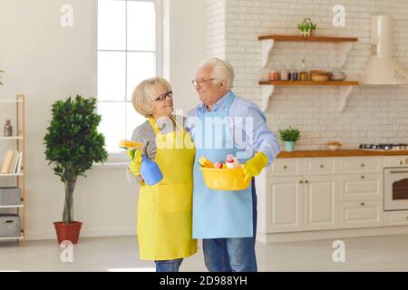 Portrait of attractive senior couple in colorful protective gloves and aprons looking at each other. Stock Photo