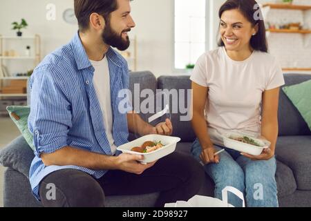 Happy young couple sitting on couch at home and having lunch ordered in meal delivery Stock Photo