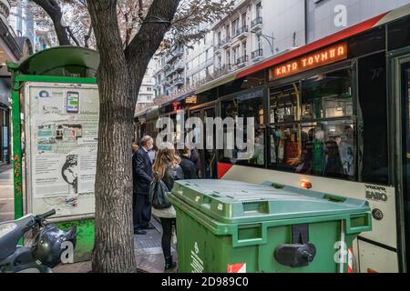 Thessaloniki, Greece - November 02 2020: People with covid-19 masks at a bus stop. Unidentified crowd with face protection in and out of an OASTH public transportation vehicle in the city centre. Stock Photo