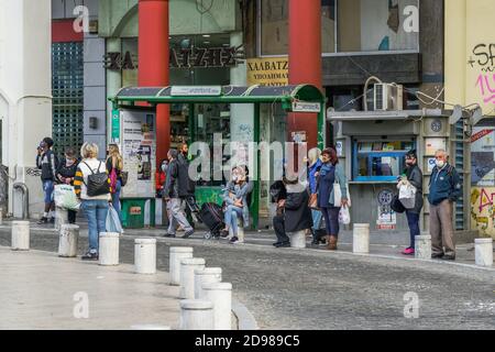Thessaloniki, Greece - November 02 2020: People with covid-19 masks at a bus stop. Unidentified crowd with face protection waiting for an OASTH public transportation vehicle in the city centre. Stock Photo