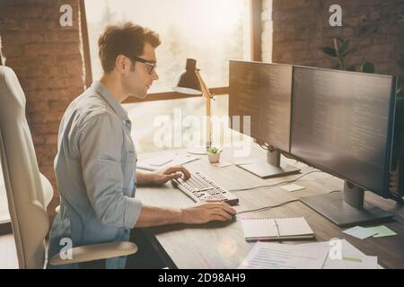 Profile side photo of focused concentrated guy sit desk work home computer solve software cyber space java script error look screen in workstation Stock Photo