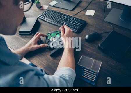 Cropped close-up view of his he nice guy hands repairing mother board part component PC on wooden table desk desktop inventing at work place station Stock Photo