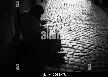 Homeless man. Blurred image of a beggar sitting on the street and waiting for alms. Black and white image Stock Photo