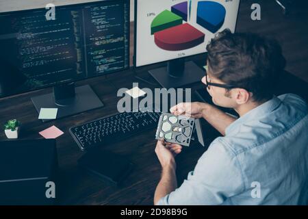 High angle view back rear spine photo of focused it specialist guy engineering sit desk look screen monitor pc hold disc analyze testing operating Stock Photo