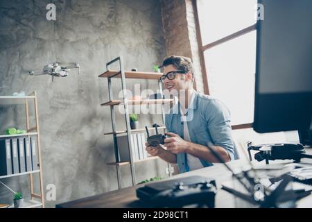 Portrait of his he nice attractive cheerful guy geek specialist expert controlling drone spending time inventing fixing at modern loft industrial home Stock Photo