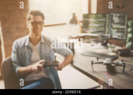 Portrait of his he blurred nice attractive cheerful cheery guy geek skilled specialist controlling drone guarantee service testing at modern loft Stock Photo