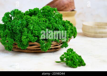 Fresh green parsley in a wicker wooden basket on a light background Stock Photo