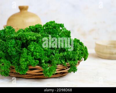 Fresh green parsley in a wicker wooden basket on a light background Stock Photo