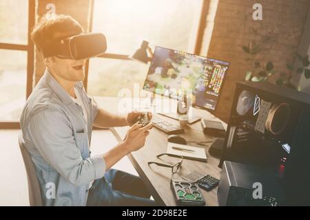 Profile side view of his he nice attractive cheerful cheery addicted guy geek freelancer playing online web network game walking vr at modern wooden Stock Photo