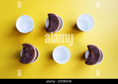 A number of semilunar candied cookies and cardboard cups organized on a bright yellow background Stock Photo
