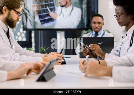 Cropped image of team of multiracial doctors using video screen projector during conference indoors, with their colleague discussing CT. African woman Stock Photo