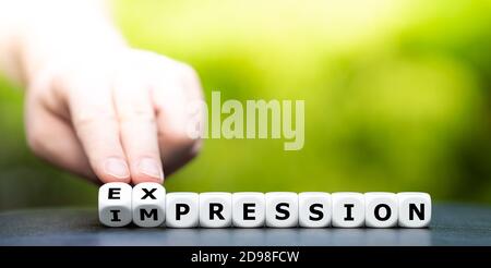Hand turns dice and changes the word "impression" to "expression". Stock Photo