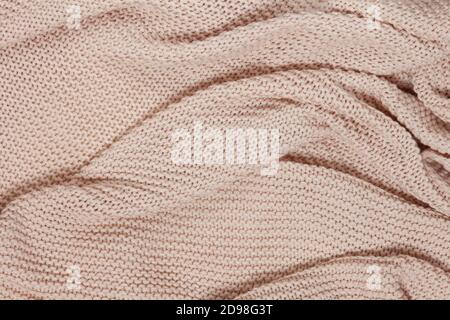 Textured surface of knitted cotton wave plaid, top view. Soft dusty pink pastel wool backdrop. Seasonal cosiness flat lay. Scandinavian minimal style. Stock Photo