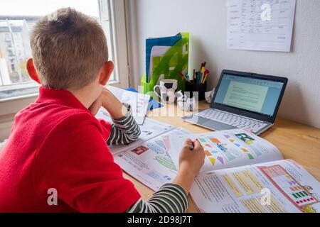 Boy looking out of window while homeschooling during corona lockdown Stock Photo