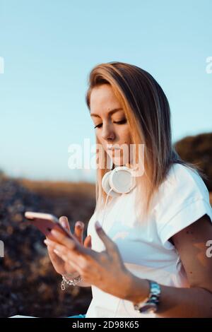 Young woman taken notes on her smartphone in the field Stock Photo
