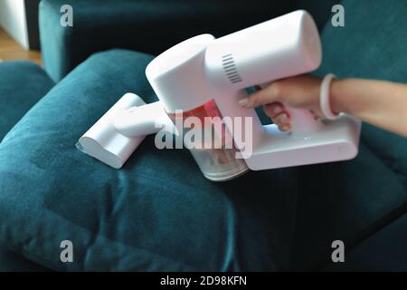 Use small vacuum cleaner to clean fabric on sofa. Stock Photo