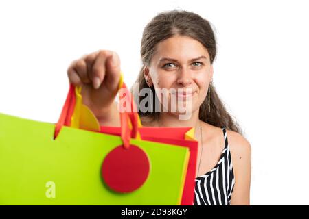 Close-up of adult woman wearing casual summer attire offering presenting gift or shopping bags to camera as consumerism lifestyle concept isolated on Stock Photo
