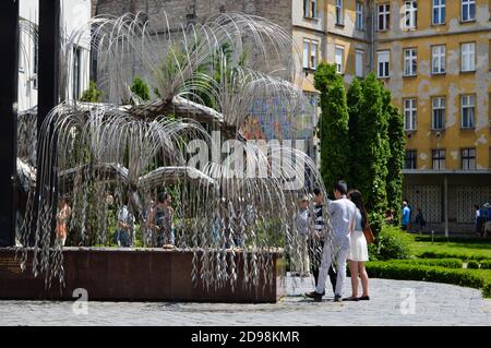 Tourists visit Raoul Wallenberg Holocaust Memorial Park, Memorial of the Hungarian Jewish Martyrs with weeping willow tree, in Budapest, Hungary Stock Photo