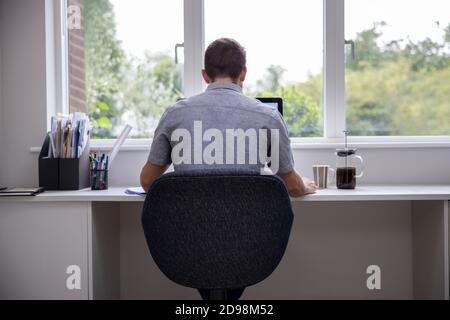 Rear View Of Man Working From Home On Computer  In Home Office Stock Photo